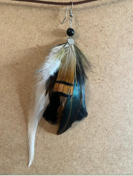 Pendiente artesanal Umbral Azul con plumas negras, blancas y reflejos azules en composición profunda y elegante
