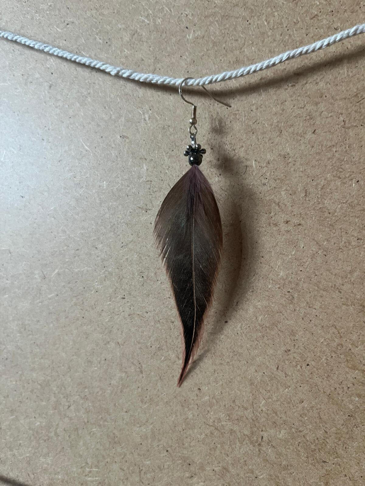 Pendiente artesanal Fuego Silencioso con pluma en tonos marrón oscuro y matices cálidos