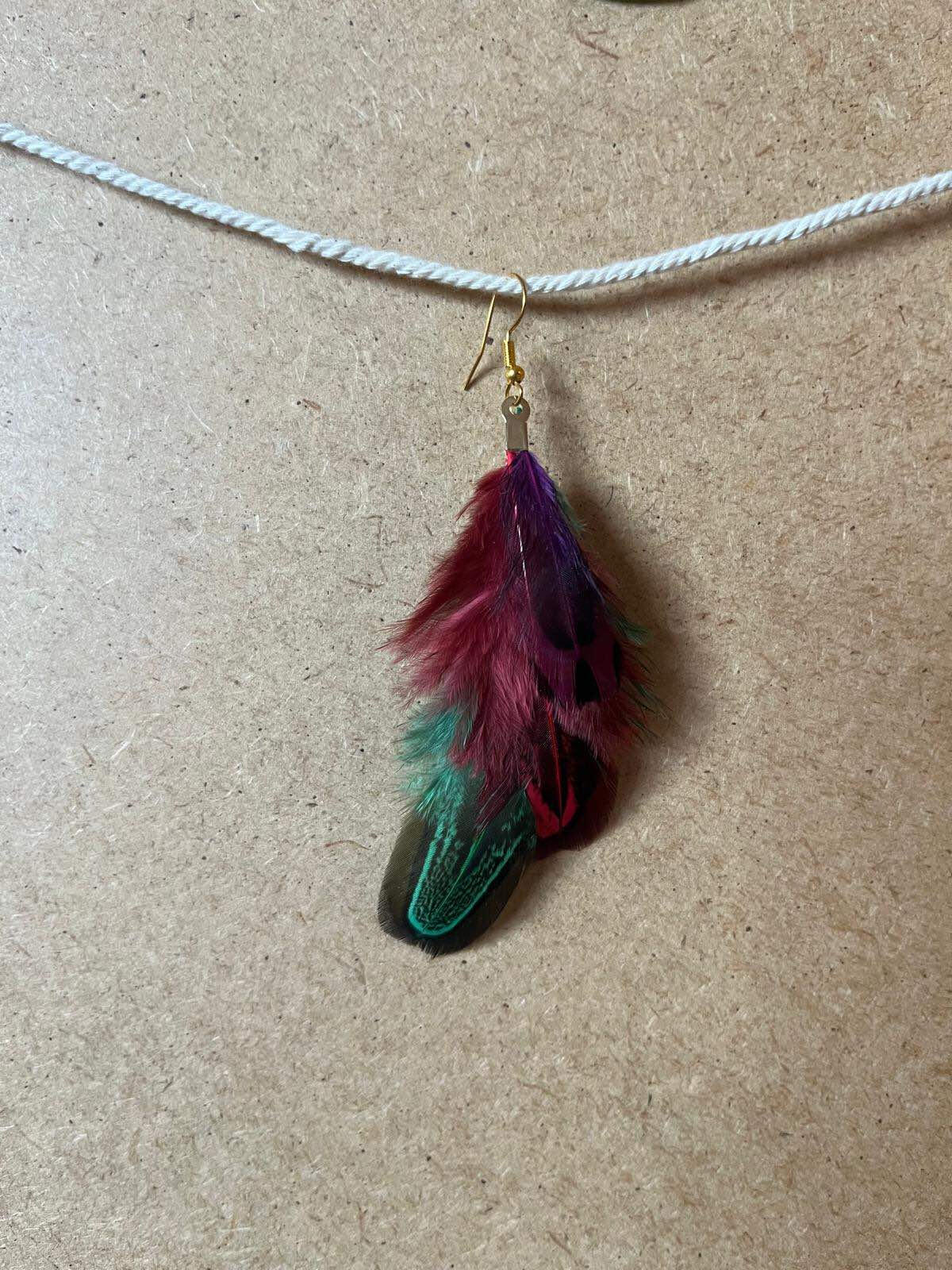 Pendiente artesanal Fuego Verde con plumas verdes y rojas de composición intensa y orgánica