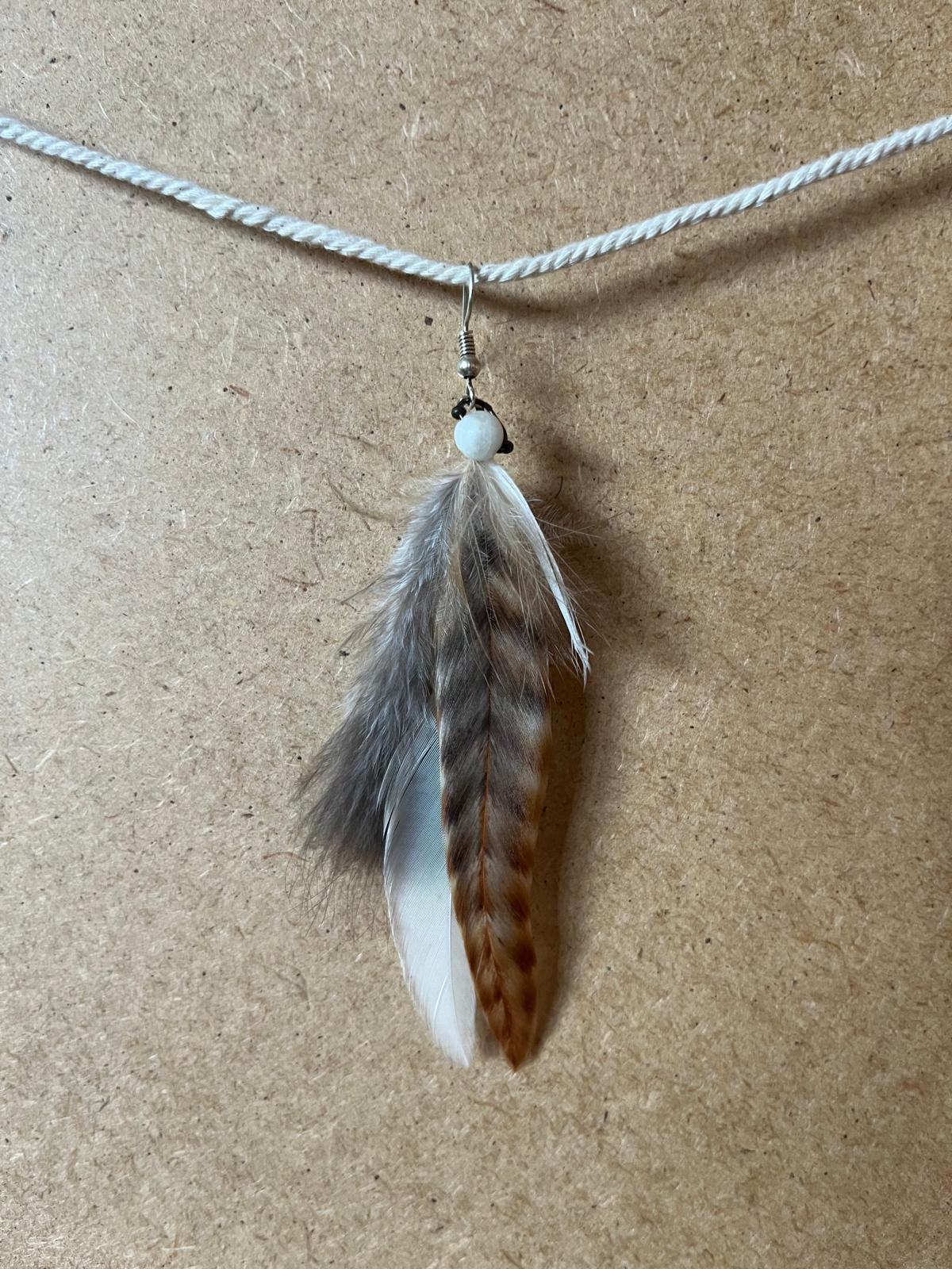 Pendiente artesanal Alma Bosque con plumas en tonos grises, blancos y marrones de inspiración natural